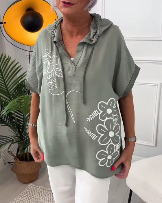 Lässige bluse mit kapuze und blumenmuster und kurzen ärmeln