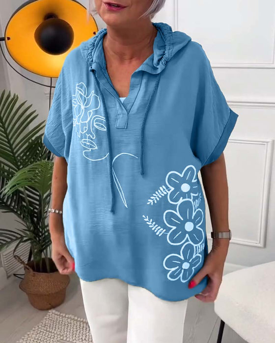 Lässige bluse mit kapuze und blumenmuster und kurzen ärmeln