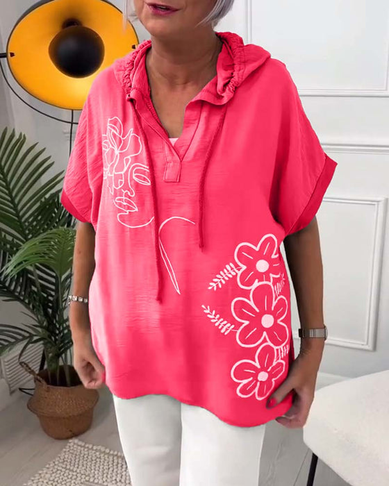 Lässige bluse mit kapuze und blumenmuster und kurzen ärmeln